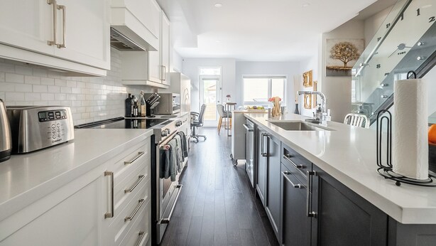 Una cocina moderna con armarios blancos, electrodomésticos de acero inoxidable y una isla central.