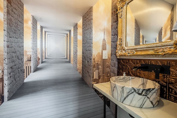 Ein Hotelkorridor mit einem мраморной Waschbecken und einem großen Spiegel.