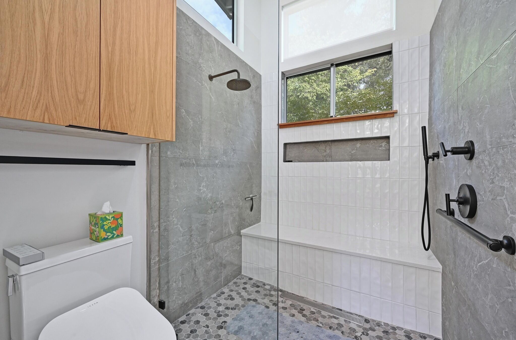 A modern bathroom with a shower, toilet, and a window.