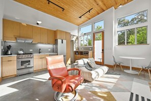 A modern kitchen with wooden cabinets, stainless steel appliances, and a large window.