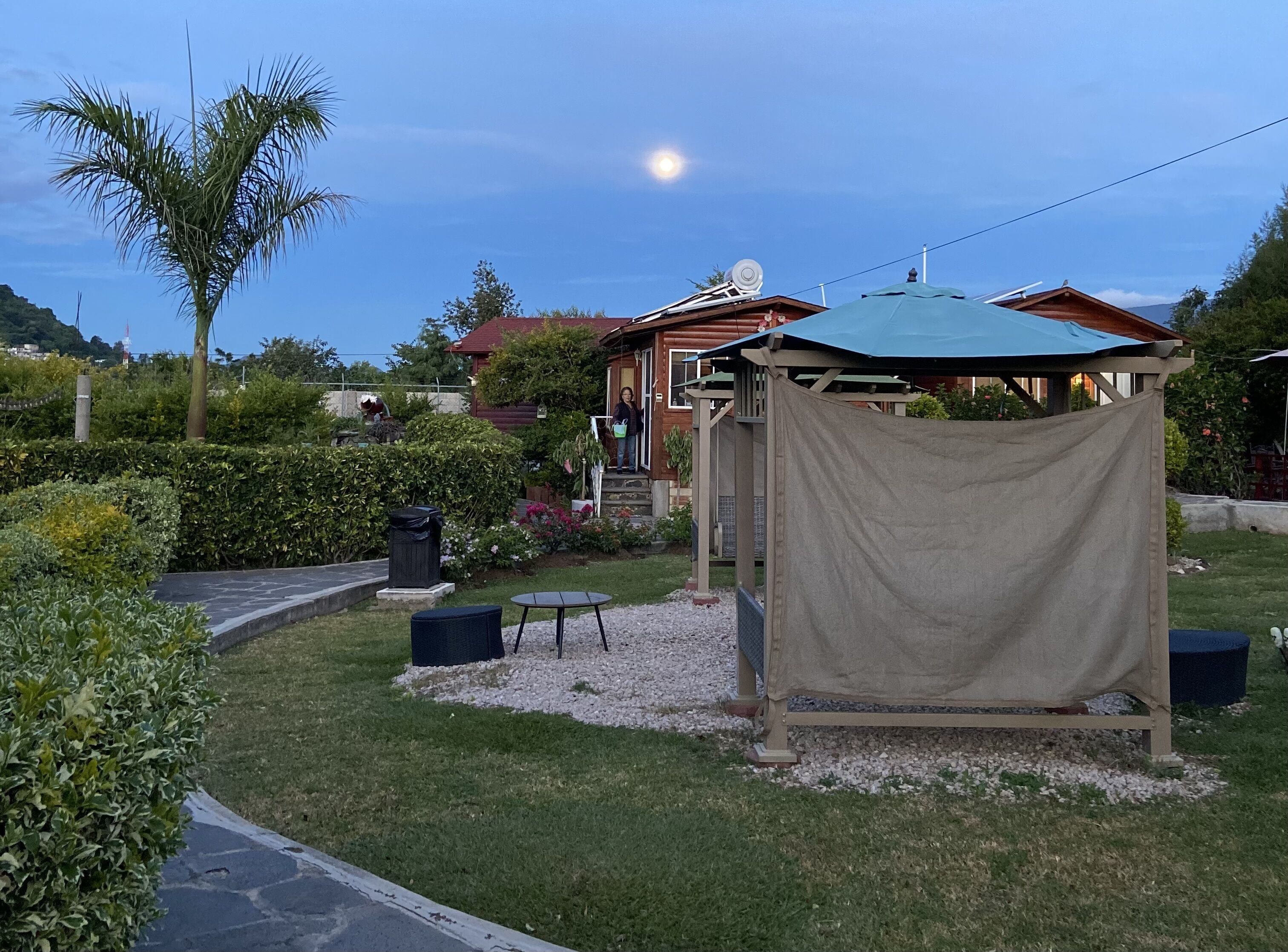 A garden with a gazebo, a small table, and a chair.