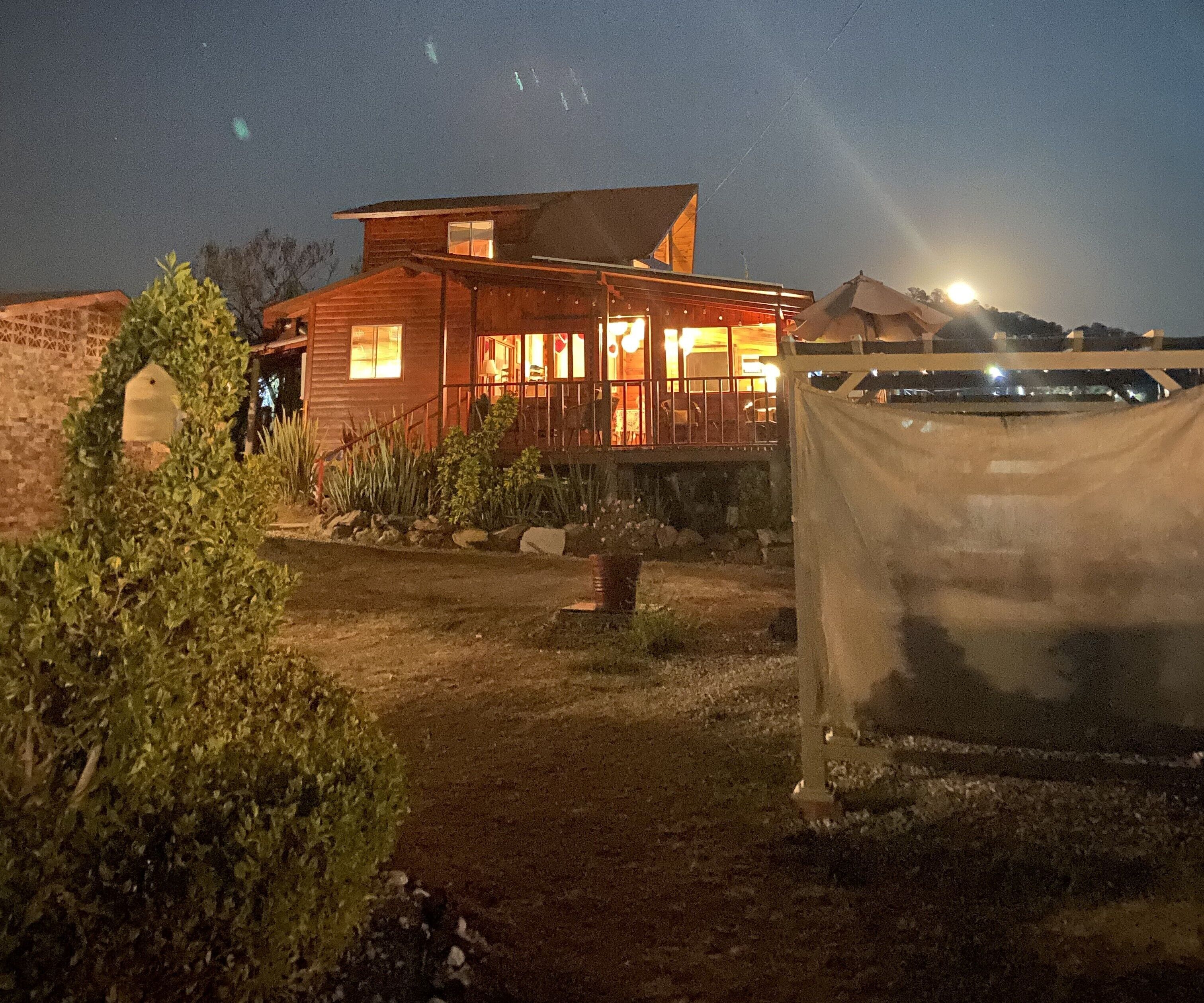 A wooden house with a porch, a covered area, and a clear view of the sky.