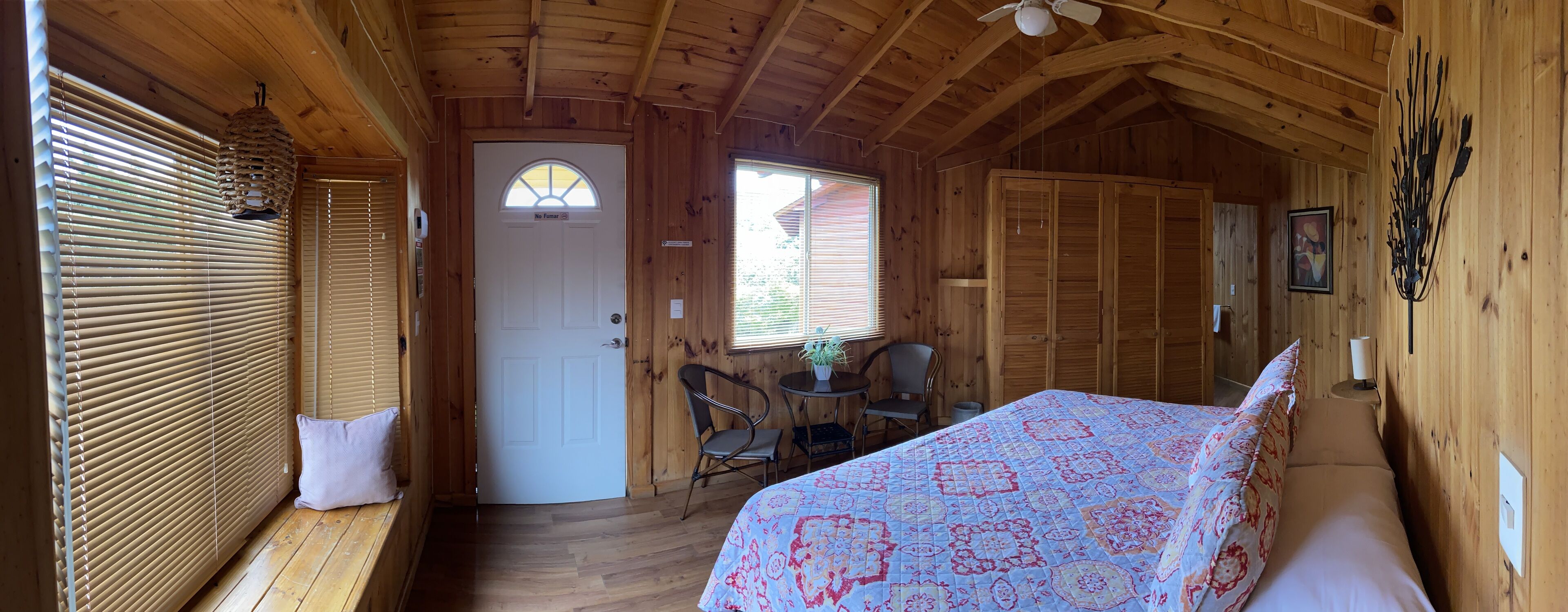 A cozy wooden cabin room with a bed, a desk, and a chair.