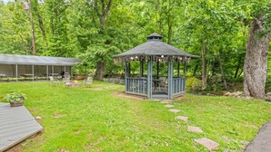 A gazebo in a lush green outdoor setting with a covered patio area in the background. - The Valley Inn  (Maggie Valley)