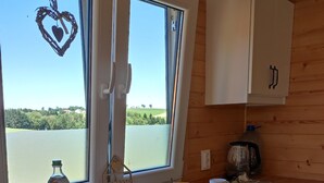 Eine Küche mit Holzausstattung, einem Fenster mit Herzdeko und Blick auf Grün.