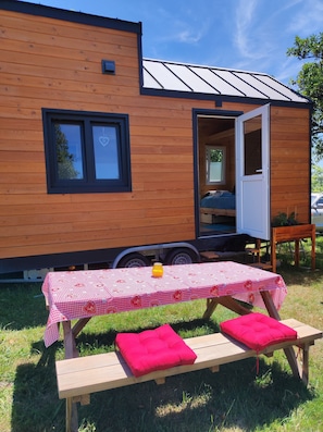 Una casa mobile in legno con tavolo e panche all'esterno.