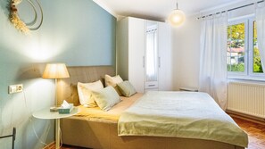 Une chambre à coucher avec un lit, une table de chevet, une lampe et une fenêtre avec des rideaux.