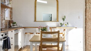 Een keuken met een eettafel, stoelen en een grote spiegel aan de muur.