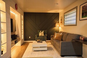 A modern living room with a sofa, a coffee table, a chair, and a television.