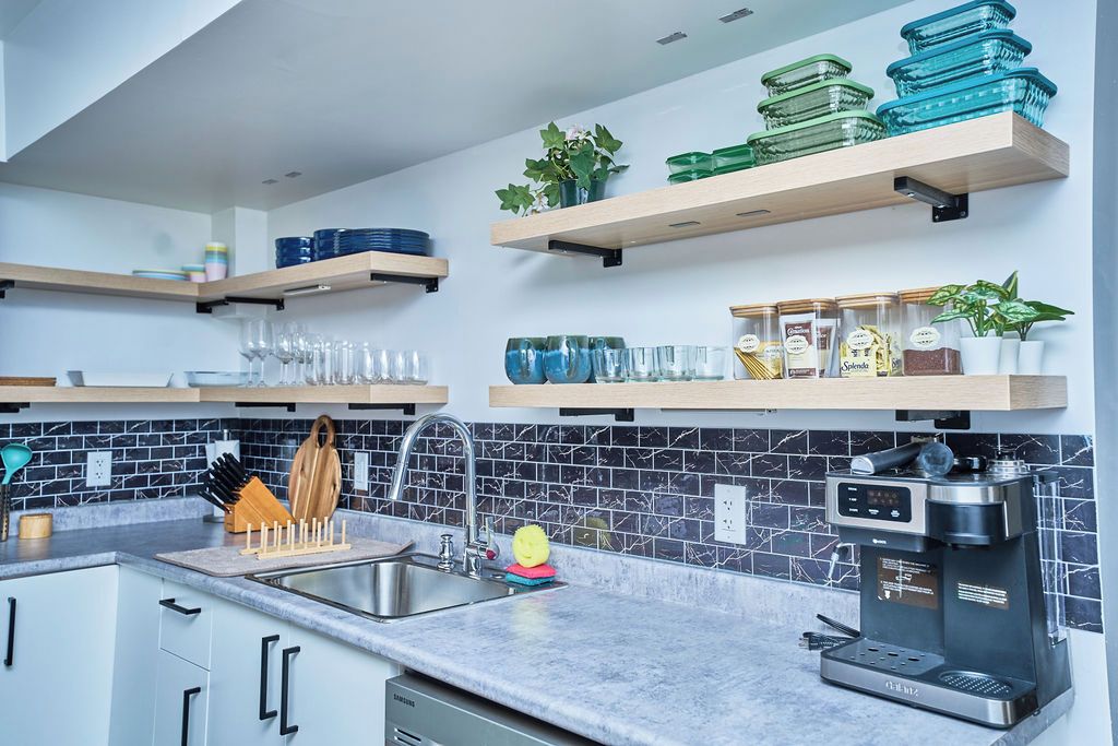 A modern kitchen with a built-in coffee maker, stainless steel appliances, and a tiled backsplash.