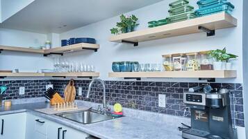 A modern kitchen with a built-in coffee maker, stainless steel appliances, and a tiled backsplash.