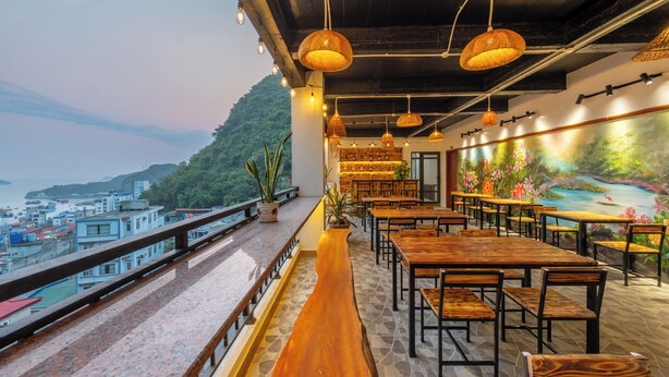 Un restaurant doté d’une terrasse offrant une vue sur le paysage urbain et les collines environnantes.