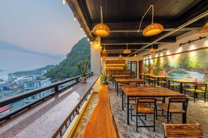 A restaurant with outdoor seating overlooking a cityscape and hills. - Cat Ba Xanh Spring Garden Hotel  (Hai Phong)