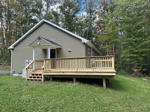 A two-story house with a wooden deck and a covered porch. - Secluded mountain home on over 10 wooded acres, modern, WiFi and pet friendly! (Westfield)