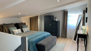 Un dormitorio con cama, un banco, un armario y un espejo.
