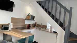 Una cocina moderna con encimera de madera, un lavamanos y un microondas integrado. Hay un comedor con una mesa y sillas.