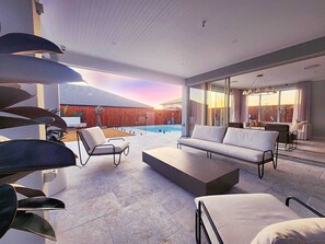 Ein modernes Wohnzimmer mit Pool, Außenbereich und einer großen Schiebeglastür zum Garten.