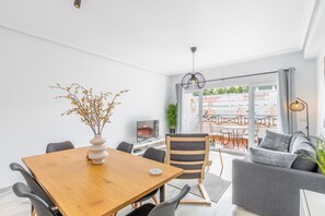 A modern living room with a dining table, sofa, and a view of the outdoors.