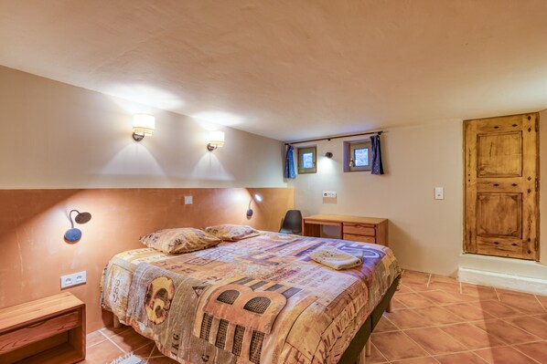 A bedroom with a large bed, a desk, a chair, and a wooden door. - Spacious villa with 25 m pool, spa & mountain views, 20 min from Montpellier (St Mathieu de Tréviers)