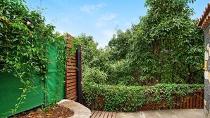 Een tuin met een houten omheining, een groene wand en een pad van stenen.