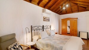 Een slaapkamer met een bed, een stoel, een kledingkast en een plafondventilator.