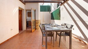 A covered patio with a dining table and chairs, a washing machine in the background, and a green wall. - Vacation Home 'Villa Charlotte' with Mountain View, Shared Pool and Wi-Fi (La Oliva)