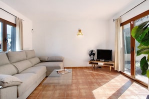 Un salon avec un canapé, une table basse, un téléviseur et un ventilateur.