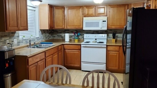 A compact kitchen with wooden cabinets, a microwave, a stove, and a refrigerator.
