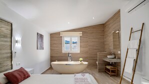 Une chambre à coucher moderne avec un grand lit, une baignoire sur pieds et un plancher en bois.