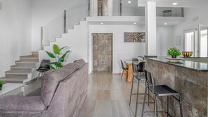 Un vaste espace de vie comprenant un escalier, un coin repas et une cuisine avec un bar.