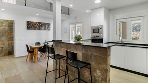 Une cuisine moderne avec un îlot en pierre, des armoires blanches et un coin repas avec des chaises.