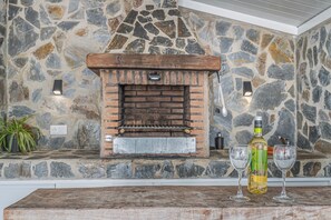 A stone wall with a brick fireplace, two glasses, and a bottle.