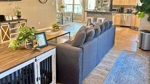 A modern living room with a sectional sofa, a dining area, and a kitchen.