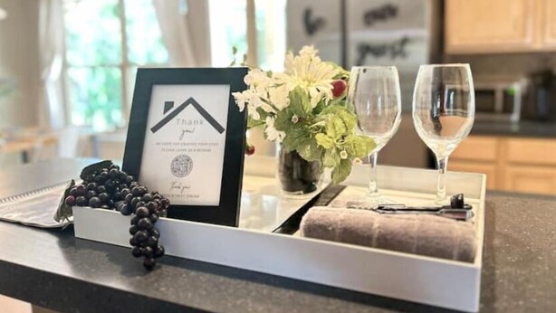 A kitchen counter with a framed certificate, a vase with flowers, and two wine glasses.