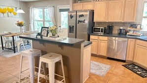 A modern kitchen with wooden cabinets, a stainless steel refrigerator, and a built-in island with stools.