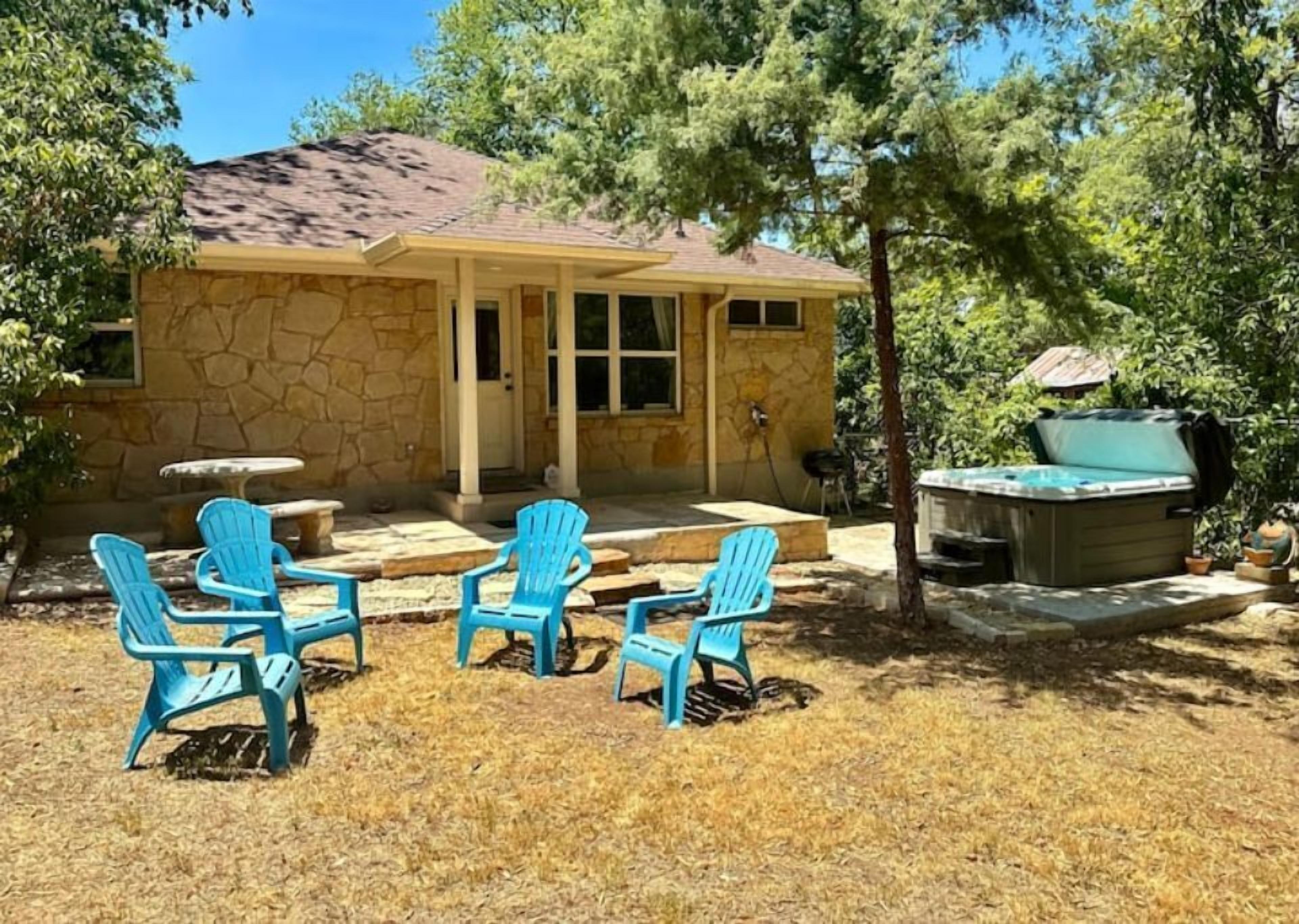 A stone house with a covered patio, outdoor seating, and a hot tub.