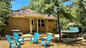 A stone house with a covered patio, outdoor seating, and a hot tub.