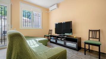A living room with a sofa, a TV, a cabinet, and a chair.