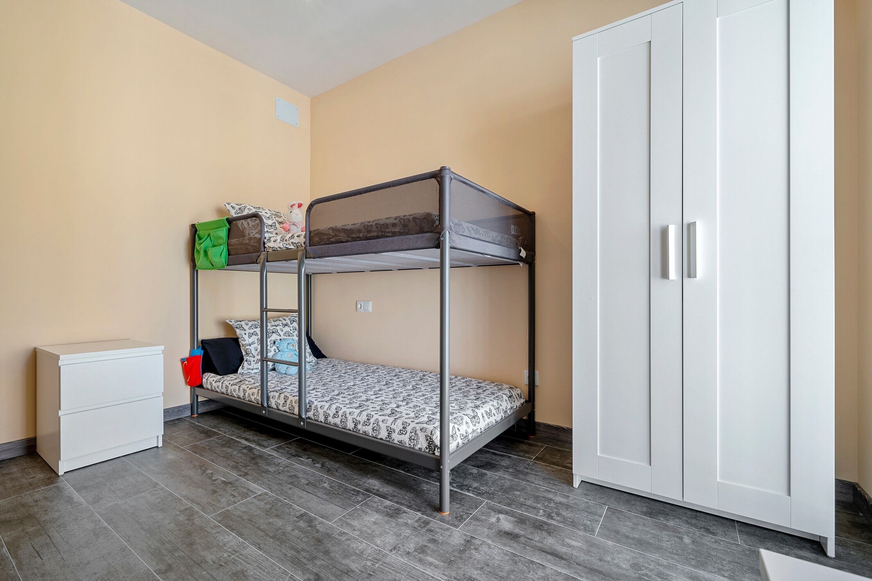 A bunk bed with a mattress, pillows, and a small white cabinet.