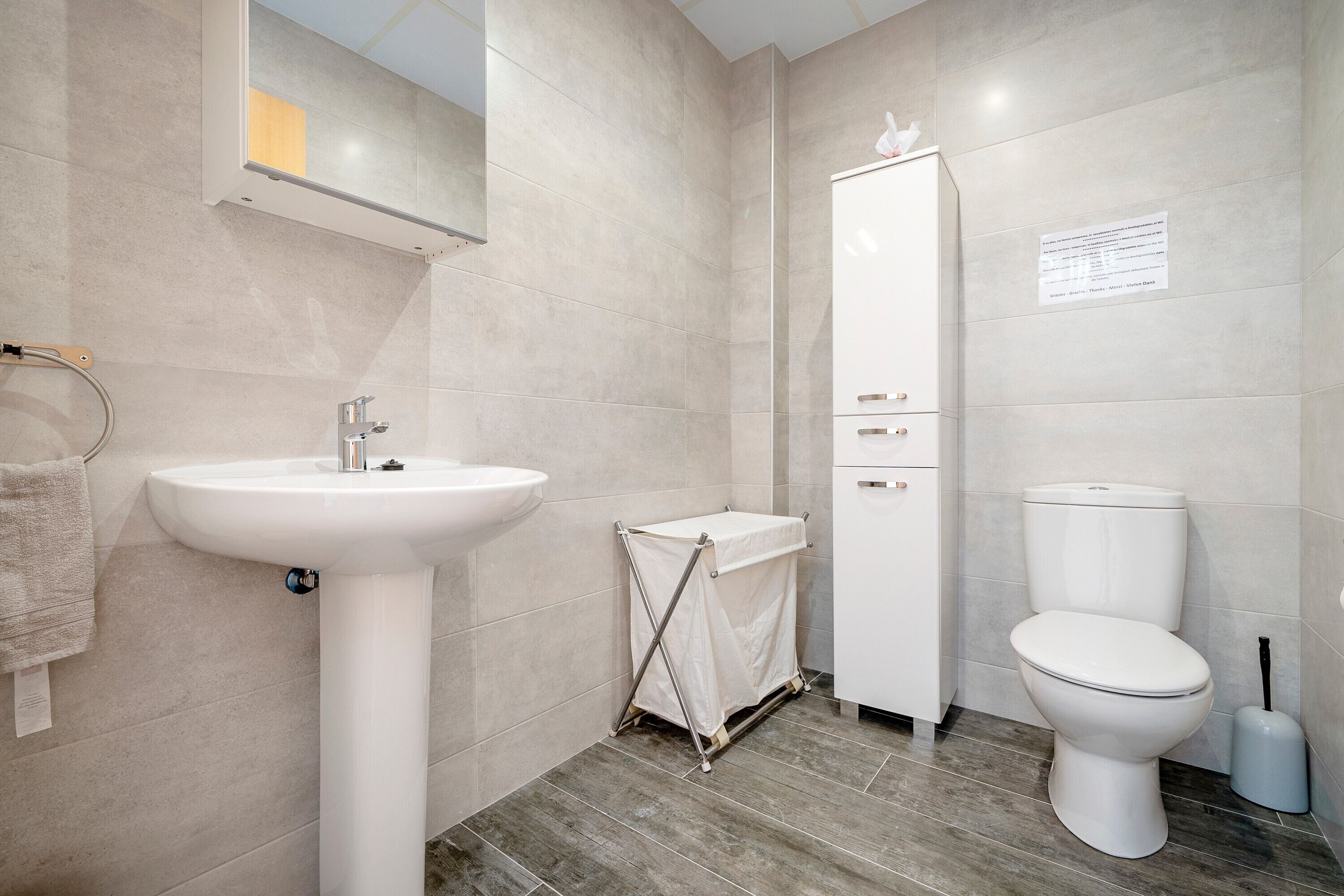 Un baño con lavamanos pedestal, inodoro y armario.