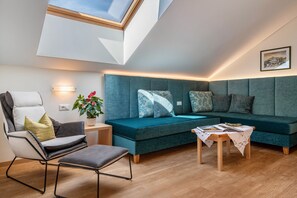 A modern living room with a skylight, a sofa, a chair, a small table, and a potted plant.