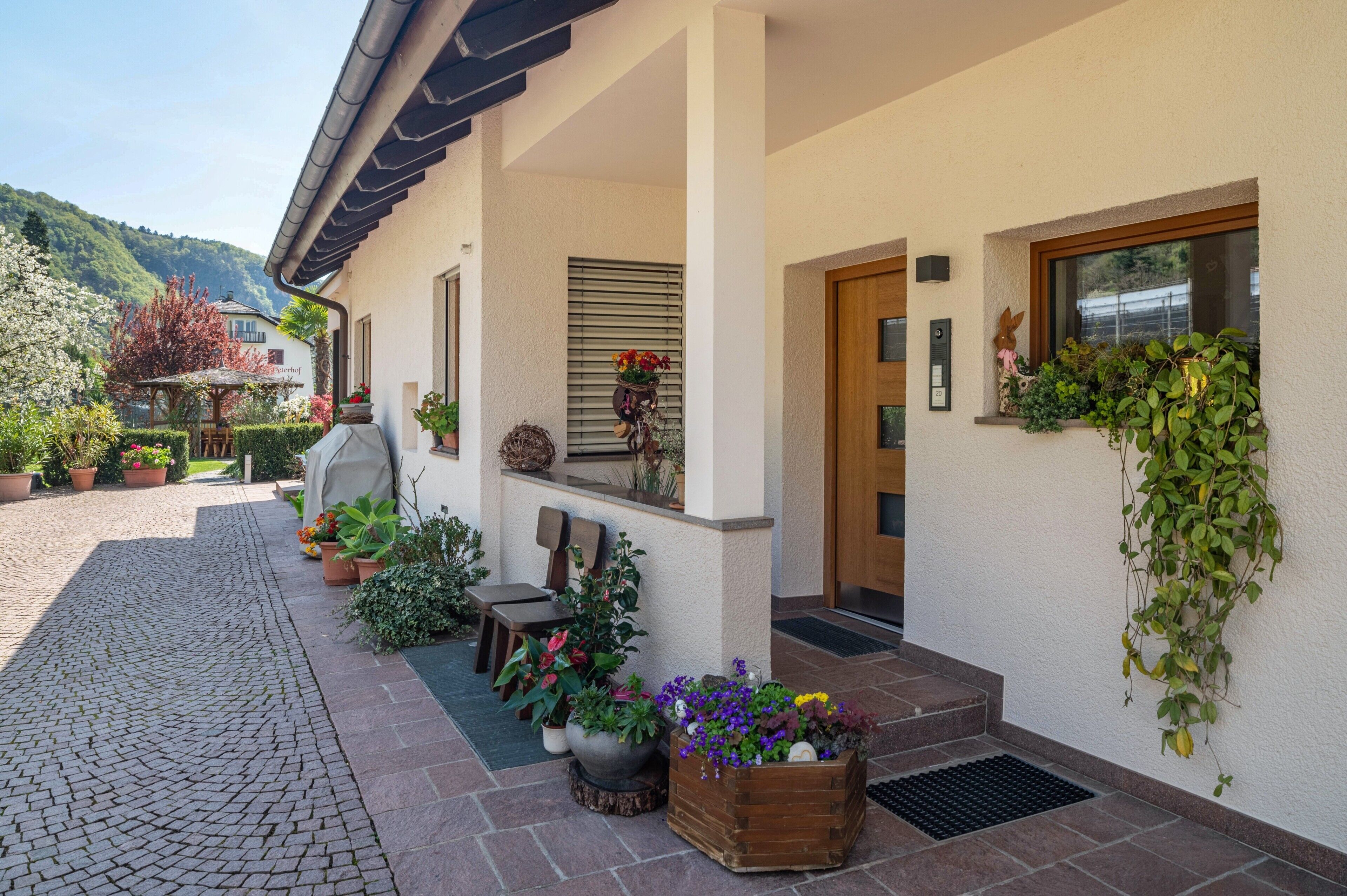 A building with a porch, potted plants, and a view of the mountains.