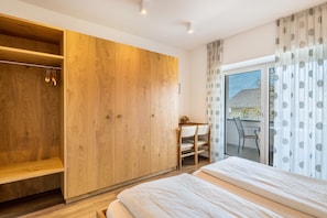 Une chambre à coucher avec un lit, une armoire en bois et un balcon équipé d’une chaise.