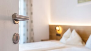 Een hotelkamer met een bed, een nachtkastje en een wandlamp.