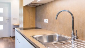 Een moderne keuken met roestvrijstalen spoelbakken, een houten accentmuur en een inbouwoven.