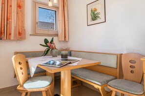 Une table à manger en bois, des chaises rembourrées, un vase rempli de fleurs et un tableau encadré accroché au mur.