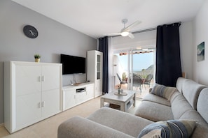A living room with a sofa, a coffee table, a TV, and a cabinet.