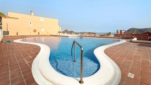 A swimming pool with a tiled deck, metal handrails, and a view of distant hills. - Vacation Apartment 'Isabel Vista Sur' with Sea View, Shared Pool and Wi-Fi (Chayofa)