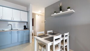 A modern kitchen with white cabinets, a dining table with chairs, and a grey accent wall. - Vacation Apartment 'Isabel Vista Sur' with Sea View, Shared Pool and Wi-Fi (Chayofa)