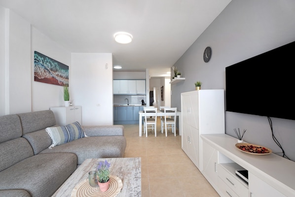 A modern living room with a sofa, coffee table, and TV stand.